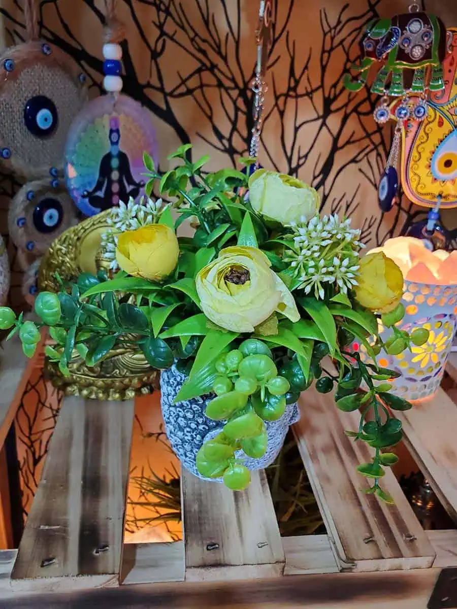 Maceta con cara de Buda con flores amarillas artificiales