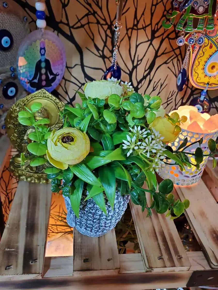 Maceta con cara de Buda con flores amarillas artificiales