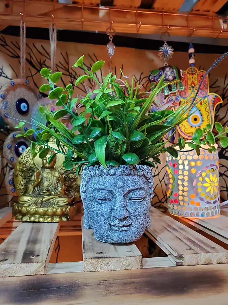 Maceta con cara de Buda con flores bordo artificiales