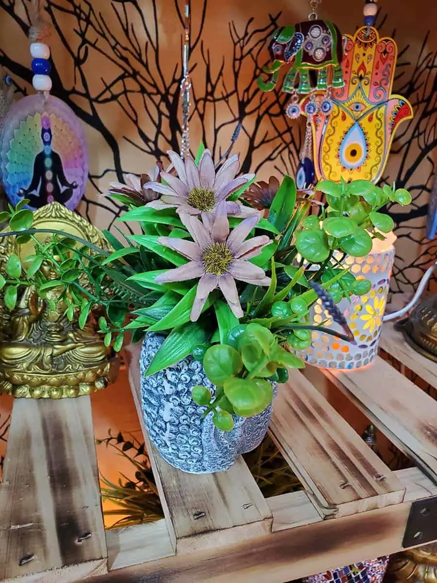 Maceta con cara de Buda con flores bordo artificiales